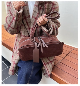 Close-up of retro brown suede tote bag with dual zippers and leather tassel details