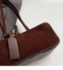 Macro detail of dark brown frosted suede shoulder bag showing stitching and texture