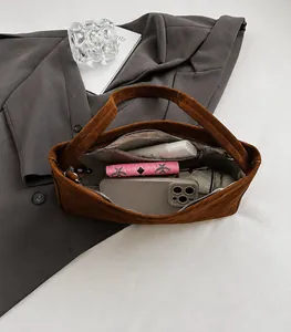Ruim interieur van de bruine suède tas met telefoon paraplu en cosmetica inhoud