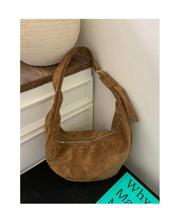 Close-up of brown suede saddle bag with metal zipper and adjustable strap details