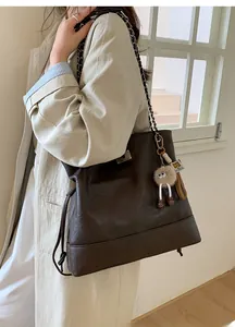 Detail of vintage large tote bag in dark brown PU leather with plush doll charm