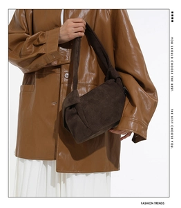 Détail du sac à bandoulière en daim marron foncé avec sangle à nœud et texture chic