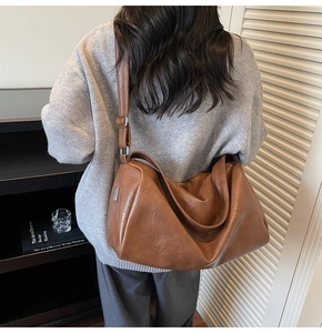Detail view of large dark brown leather tote bag showing soft texture and adjustable strap