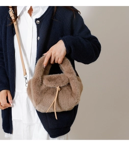 Detail of light khaki faux fur handbag showing plush texture and leather strap detail