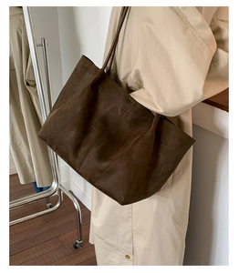 Macro detail of the dark brown suede tote bag showing texture and slim shoulder strap