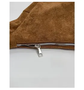Detail of smooth silver metal zipper and brown suede texture on the casual crossbody bag