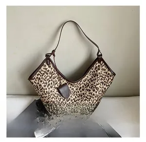 Detail view of large leopard print tote bag with brown leather trim and soft hobo structure