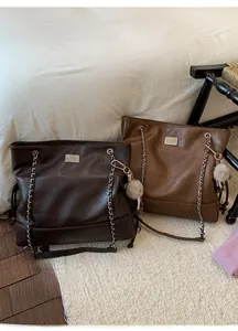 Detail of vintage tote bags in dark and light brown leather with silver chain straps