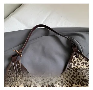 Close-up of leopard print canvas tote with brown leather handles and knot detail
