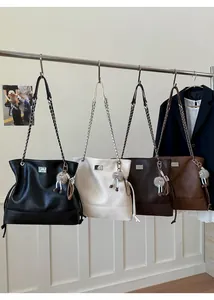 Detail shot of four large leather tote bags with metal chains and plush doll charms
