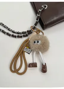 Detail of creative plush charm with large eyes and long legs on a brown leather bag chain