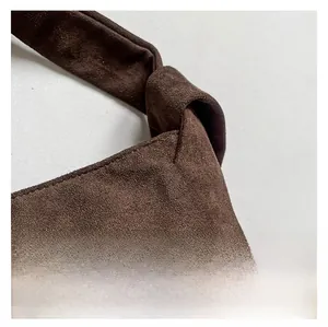 Gros plan d'un sac à main en daim marron foncé avec un nœud décoratif sur la bandoulière