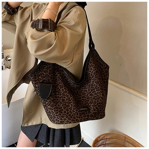 Detailed close-up of leopard print canvas tote bag with black faux leather trim and strap