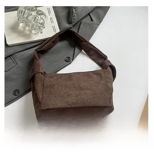 Détail du sac à bandoulière en daim marron foncé avec un nœud sur la bandoulière