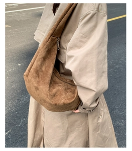 Close-up of brown suede crossbody bag with wide strap and metallic zipper closure