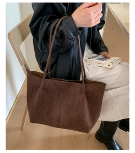 Detail of coffee brown suede tote bag with leather straps on a stylish model