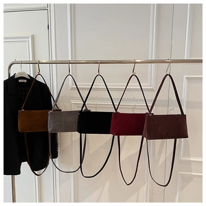 Rij minimalistische matte suède okseltassen in vijf trendy herfstkleuren aan hangers