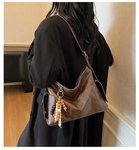 Detailed view of brown crossbody bag featuring retro texture and boho beaded tassel accessory