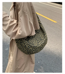 Dettaglio di una borsa a mezzaluna grande con stampa leopardata indossata a spalla