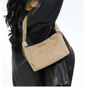 Détail du sac à bandoulière en daim camel avec bandoulière nouée sur veste noire