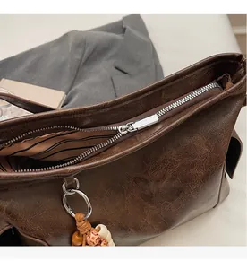 Detail of smooth silver zipper and striped lining on vintage brown crossbody bag
