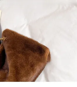 Dettaglio della texture in peluche marrone e della tracolla a catena dorata della borsa