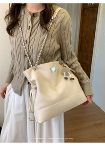 Detail of cream leather tote bag with metal chain strap and cute plush charm decor