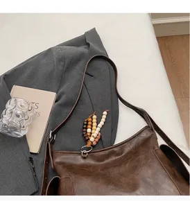 Detail view of large dark brown bucket bag with decorative wooden beads on a white surface