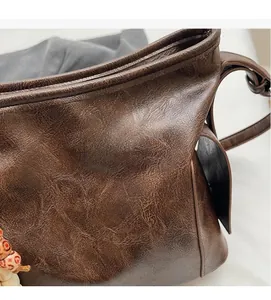 Detail of soft brown oil-wax leather texture with visible stitching and wooden bead charm