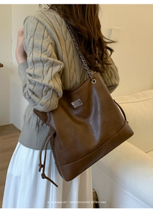 Detail of vintage brown tote bag featuring silver chain strap and drawstring design