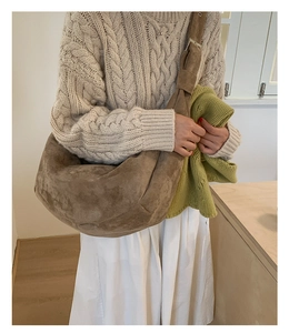 Brown suede half-moon shoulder bag styled with an elegant beige cable-knit sweater