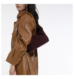 Détail de la texture d'un sac cabas en daim violet foncé porté avec un trench marron