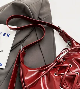Detailed shot of dark red glossy leather bag featuring criss-cross lace-up design and silver eyelets