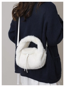 Detailed macro view of soft white faux fur texture and leather strap on a plush handbag
