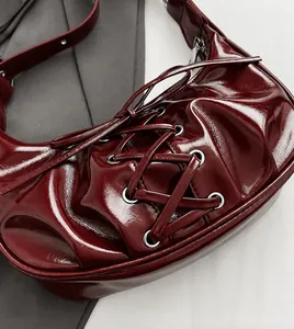 Close-up of deep red glossy baguette bag with criss-cross lace details and silver hardware