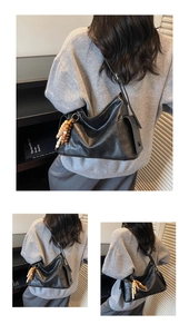 Detail of black faux leather crossbody bag with wooden bead tassel and side flap pocket