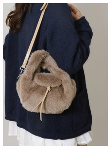 Detailopname van een zachte bruine pluche crossbodytas gestyled met blauw breigoed