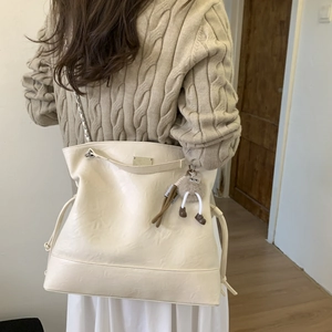 Détail du grand sac cabas en cuir crème avec texture vintage et breloque peluche