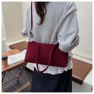 Detail van bordeauxrode suède crossbodytas met zachte textuur en zilveren metalen gesp