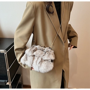 Détail du sac seau pelucheux avec fermoir doré et chaîne sur une tenue avec blazer brun