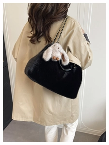 Détail du sac en fausse fourrure noire avec chaîne dorée et breloque lapin