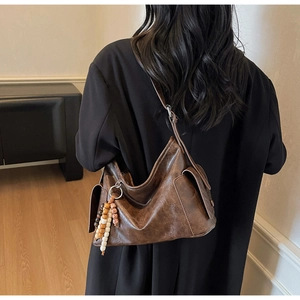 Detail of vintage dark brown faux leather crescent bag with ethnic beaded charm