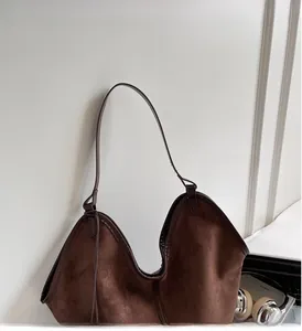 Detail of the dark brown suede tote bag featuring a slim shoulder strap and durable edges