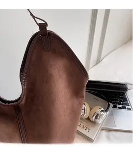 Detail of soft brown suede tote bag with leather straps in a cozy office setting