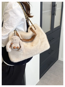 Dettaglio borsa tote beige in peluche con manico in pelle, catena oro e charm a coniglio