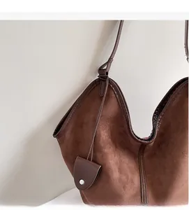 Detailed macro view of the brown suede tote bag with matching leather trim and small pouch