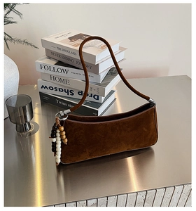 Détails d'un sac à bandoulière en daim mat marron foncé avec perles en bois et ferrures