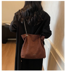 Vue détaillée d'un sac seau rétro en daim marron avec bandoulière chaîne porté au dos