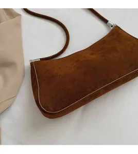 Gros plan détaillé de la texture en daim marron du sac baguette et boucle argentée