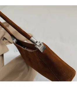 Gros plan sur la boucle métallique argentée et la fermeture éclair du sac en daim marron